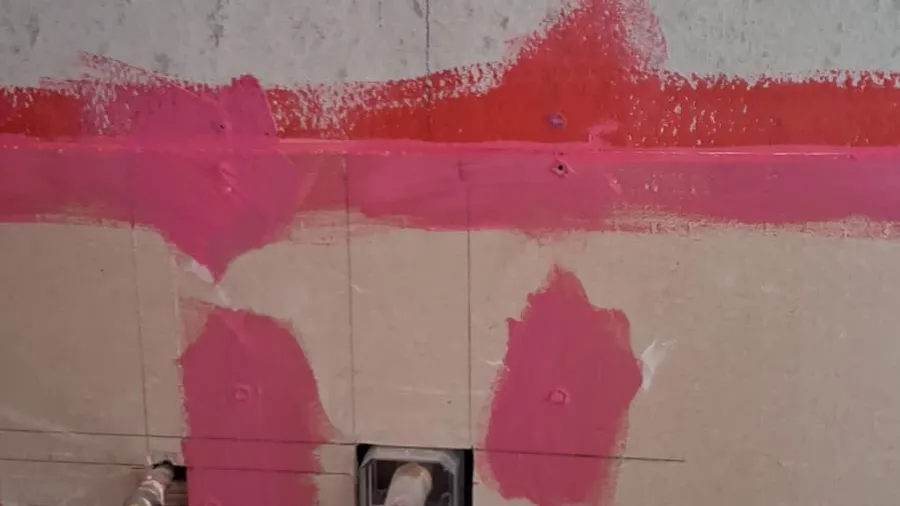 Pink waterproofing membrane applied to shower walls before tile — Butler project